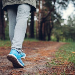 Woman tourist walking in spring forest. Close up of shoes. Sport, traveling and tourism concept